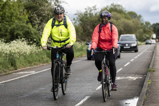 Two riders riding to work on a rural road with bike lanes