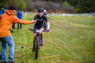 A rider taking a bottle from their support crew during a mountain bike race
