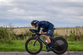 An Ineos Grenadiers rider cycling through a field