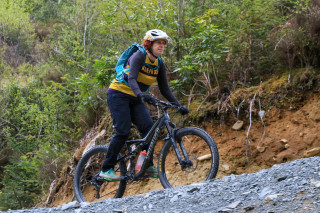 A mountain bike rider out of the saddle riding up a climb