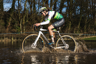 Millie Couzens riding through deep water during a cyclo-cross race