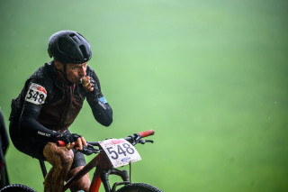 A mountain biker having a gel during a wet race
