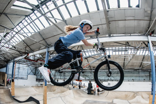 A BMX freestyle rider competing at an indoor venue in the UK.