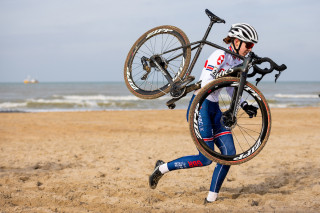 Josie Nelson running and carrying her bike during a cyclo-cross race