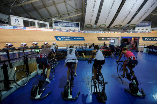 The women's team pursuit squad warm up on static trainers, while the men's team pursuiters take to the track.