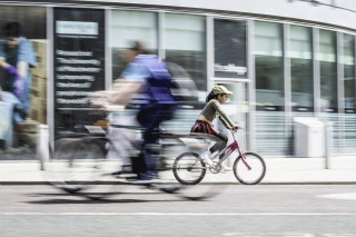 Girl riding bike through the Manchester city centre.