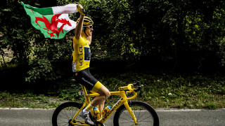 Geraint Thomas riding with the Welsh Flag on the final stage of the 2018 Tour de France after a historic win.