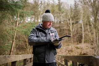 A male commissaire writing on a clipboard at a mountain bike event
